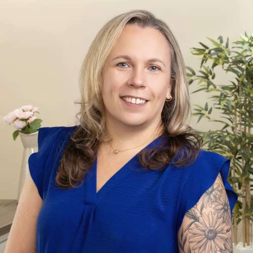 Smiling woman in blue blouse with arm tattoo