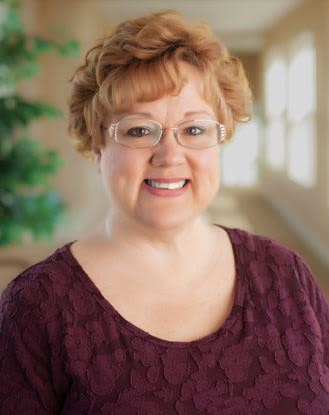 Smiling woman with glasses in indoor hallway