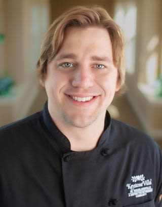 Smiling chef in black uniform indoors