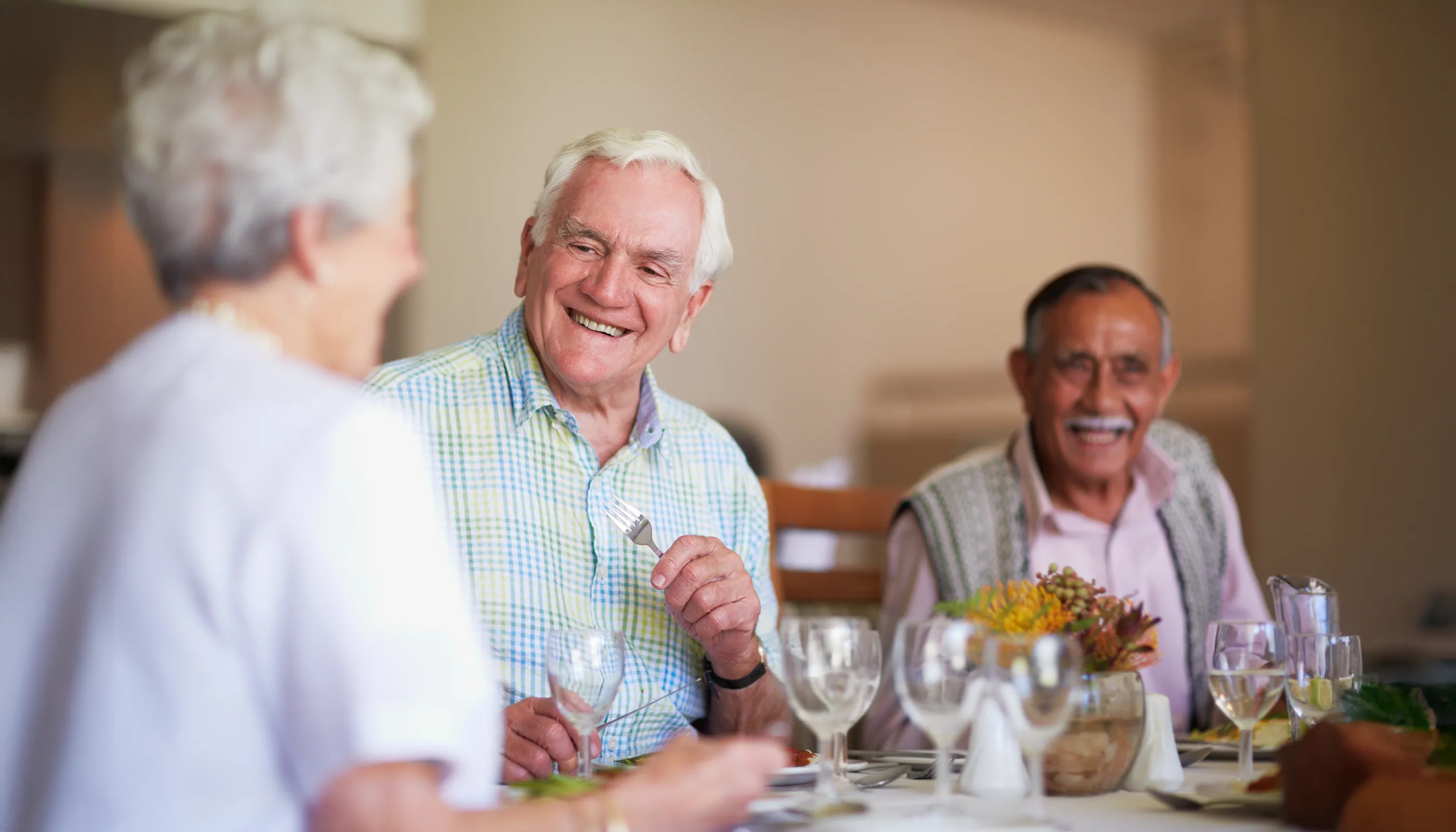 Seniors smiling and dining together at table